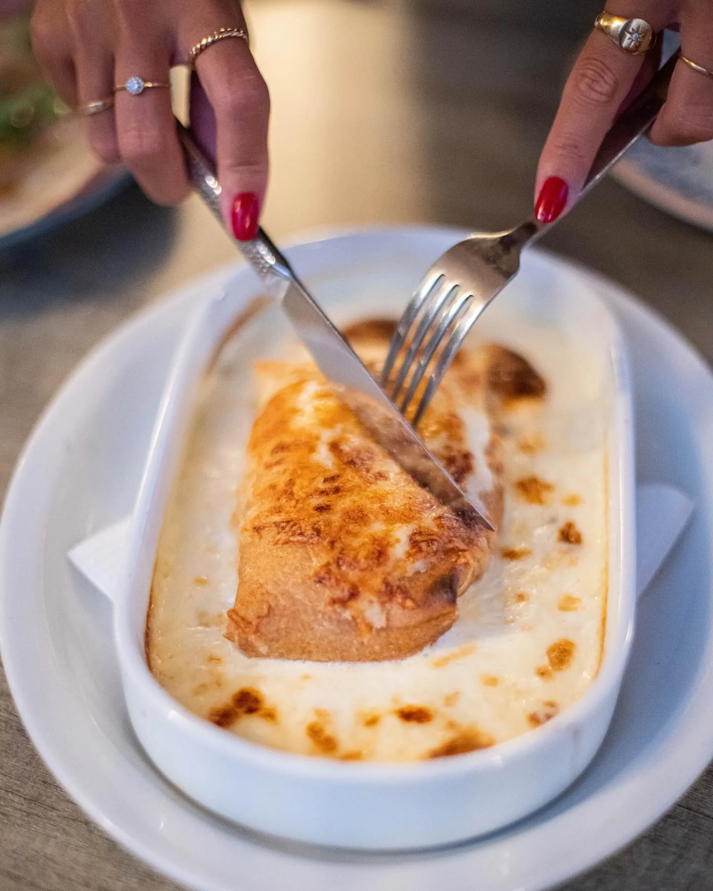 Manos cortando un gratinado